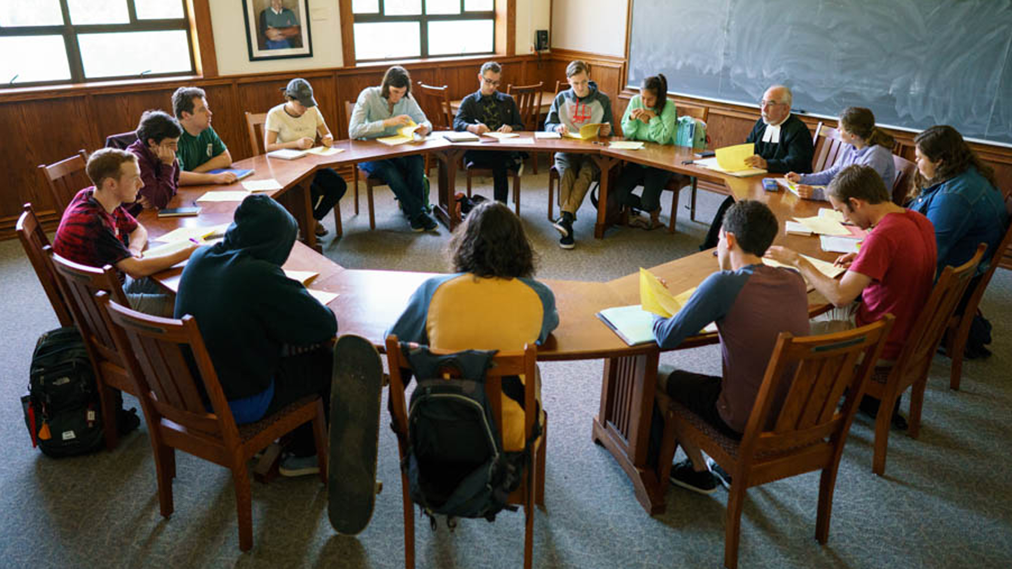 Students looking at books while sitting around a round table in seminar class