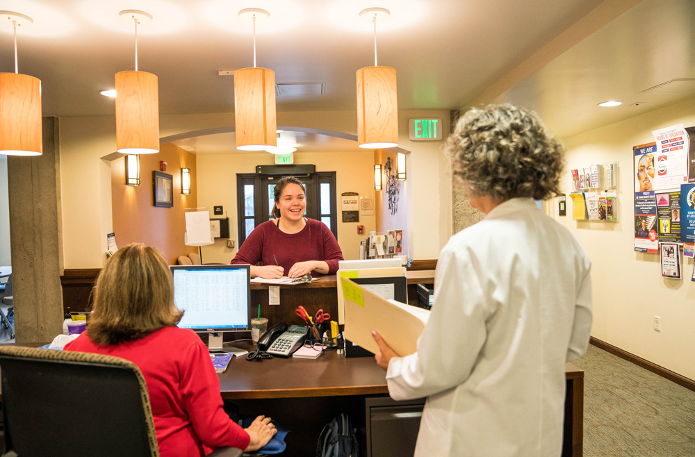 A girl smiling while filling out paperwork inside of the Health and Wellness Center