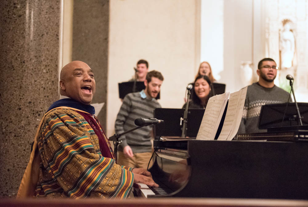 A man smiling while playing a piano and singing during mass