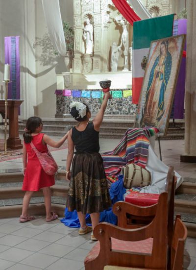 A child and mother in front of the virgin mary in the chapel