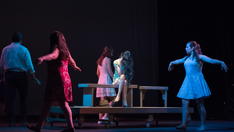 Actors walking around in a circle with their arms out during a performance on stage in LeFevre Theatre