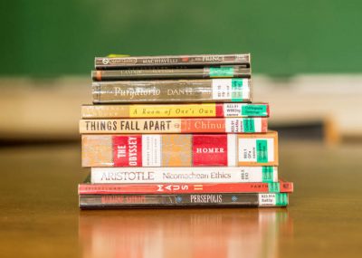 A stack of seminar books including the Odyssey and Aristotle on a table