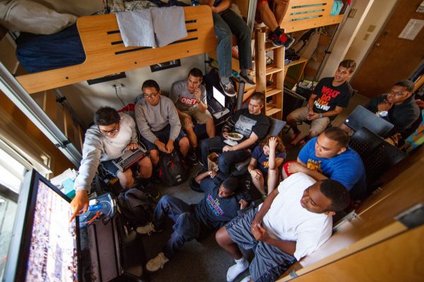 Students crowded into a dorm room watching a basketball game