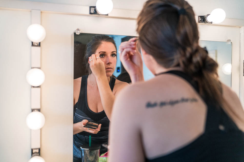 An actress looking in the mirror putting on makeup back stage of LeFevre Theatre