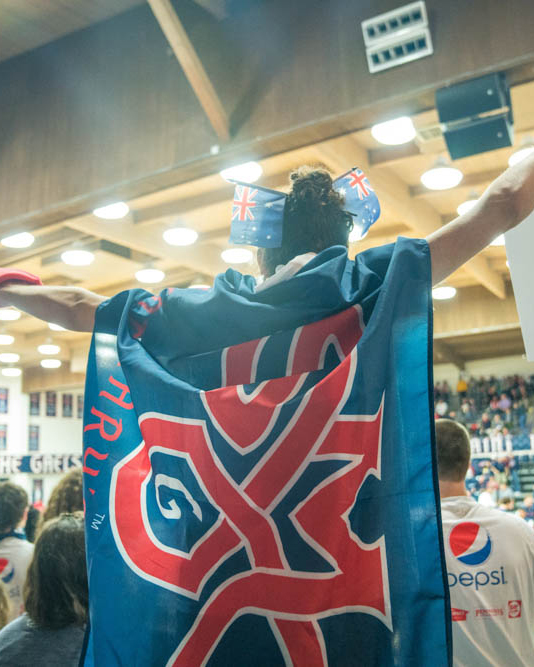 Student wearing SMC flag as a cape in the stands of UCU Pavilion