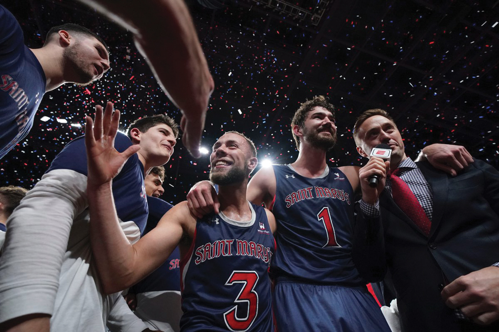 Basketball players shaking hands with confetti falling behind them in UCU Pavilion