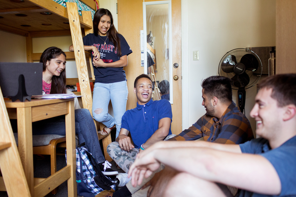 Students hanging out in a dorm room smiling and laughing